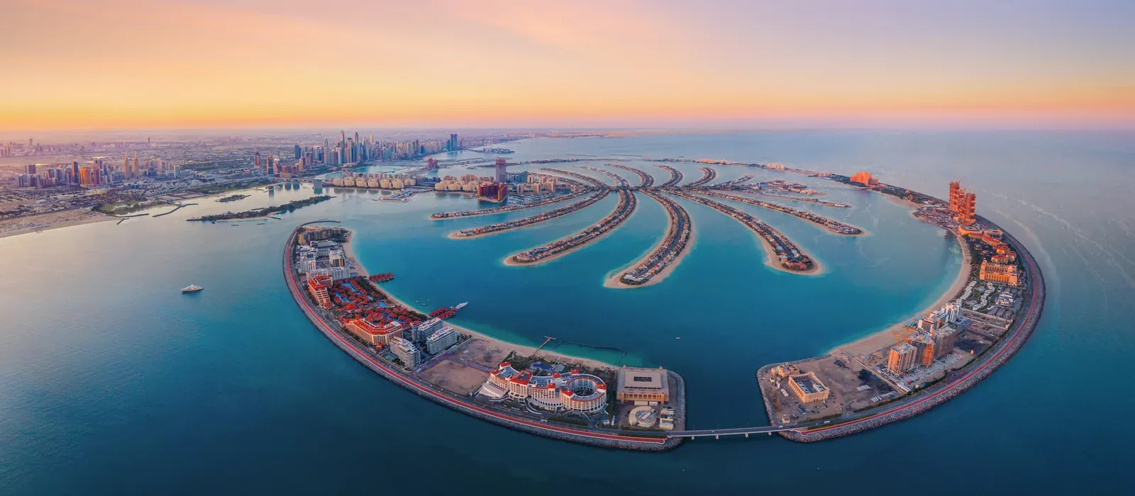 Palm Jumeirah in Dubai from the air at dusk, the city's towers behind it