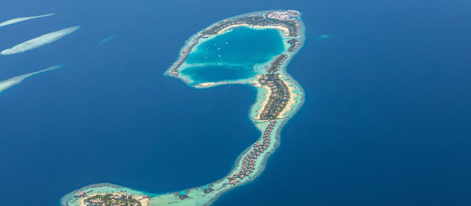 An atoll in the Maldives from the air, its reef curling through deep blue water